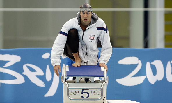 Phelps prepares to race, his earbuds dangling.