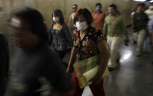 People wear surgical masks as a precaution against the swine flu outbreak on their way to subway trains in Mexico City,