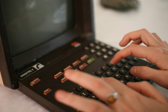 close up of hands tying on a dark Minitel terminal